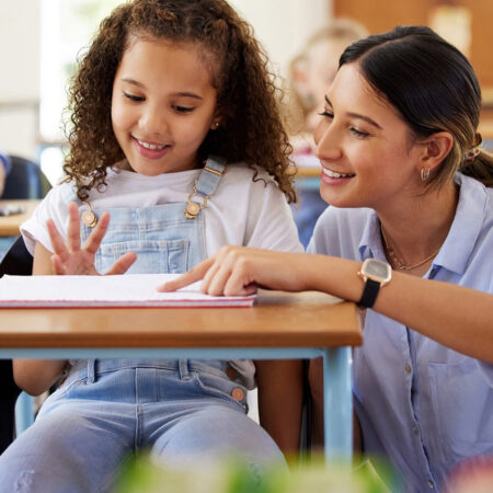 A teacher helping students with coursework in class.