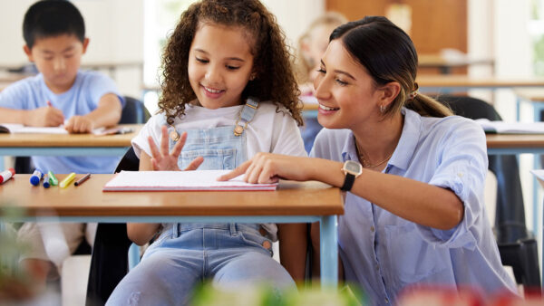 A elementary education teacher helping students with coursework in class.