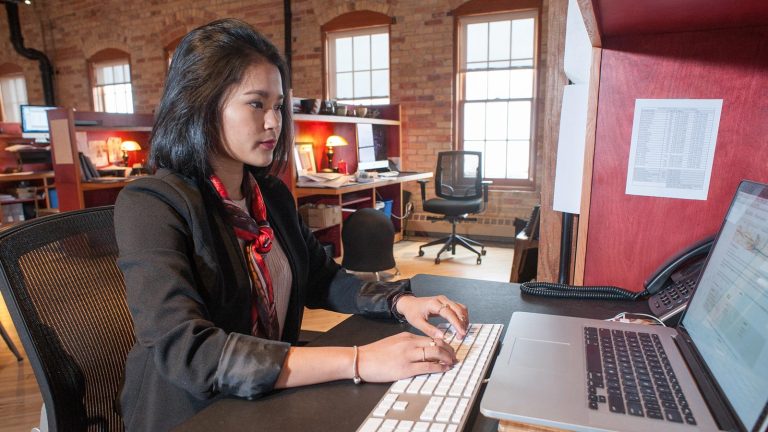 St. Scholastica's Zhara Davies working at a desk on a computer at her internship in Duluth, MN.